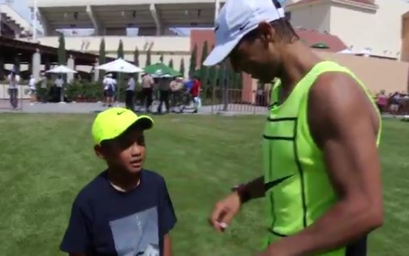 Nadal gives young boy a football lesson, and signs his hat 